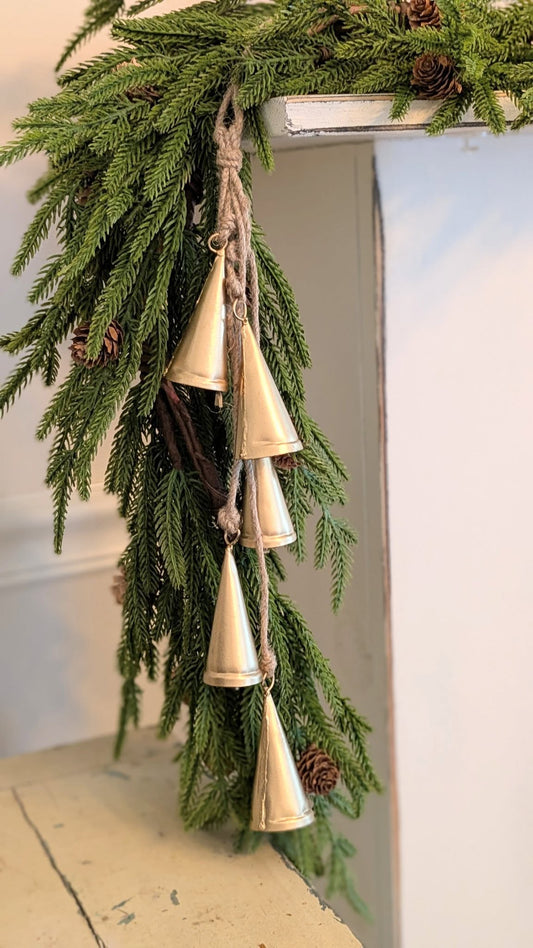 Decorative hanging with greenery and gold bells on a white surface.